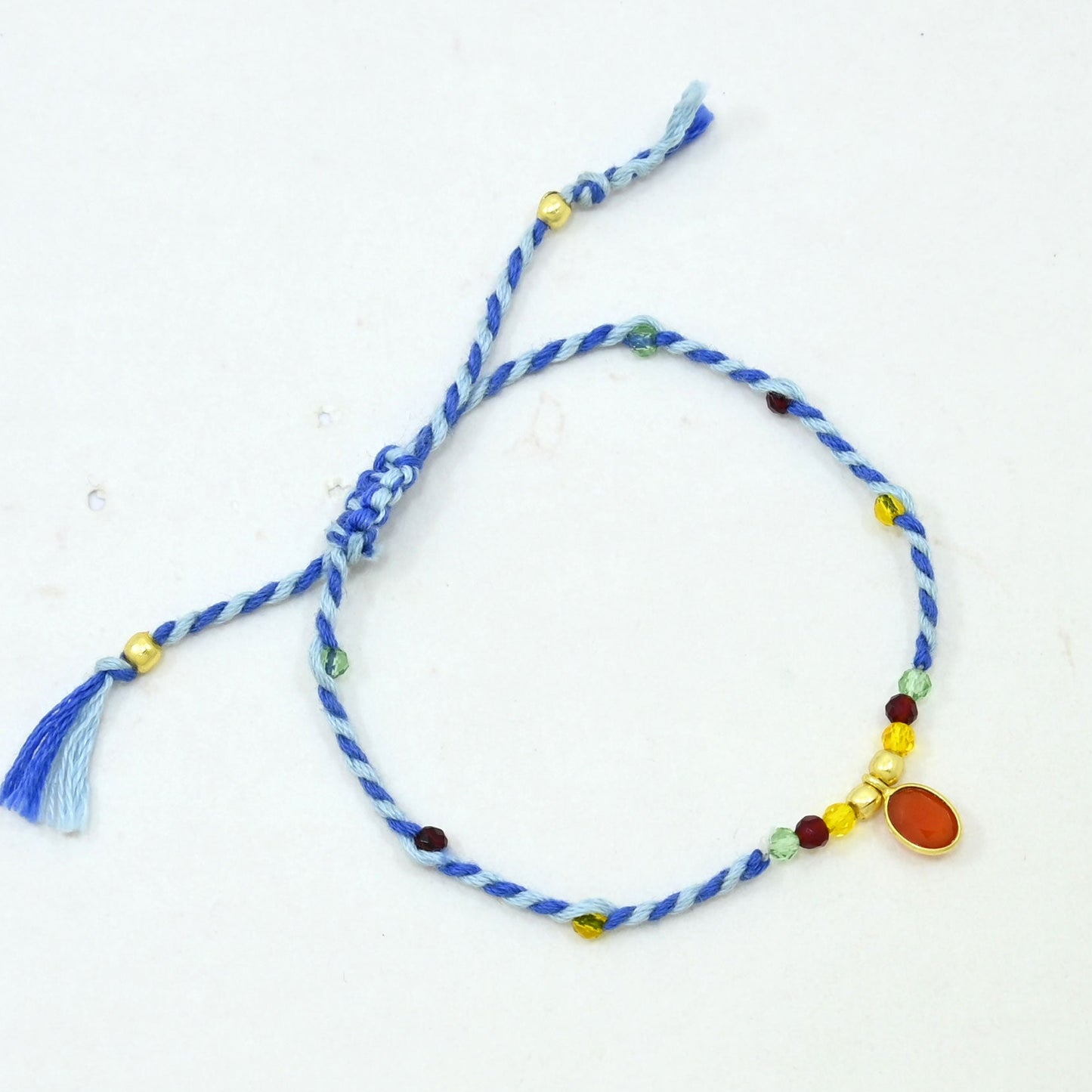 A blue and white twisted cord bracelet with small multicolored beads and a dangling blue tassel.