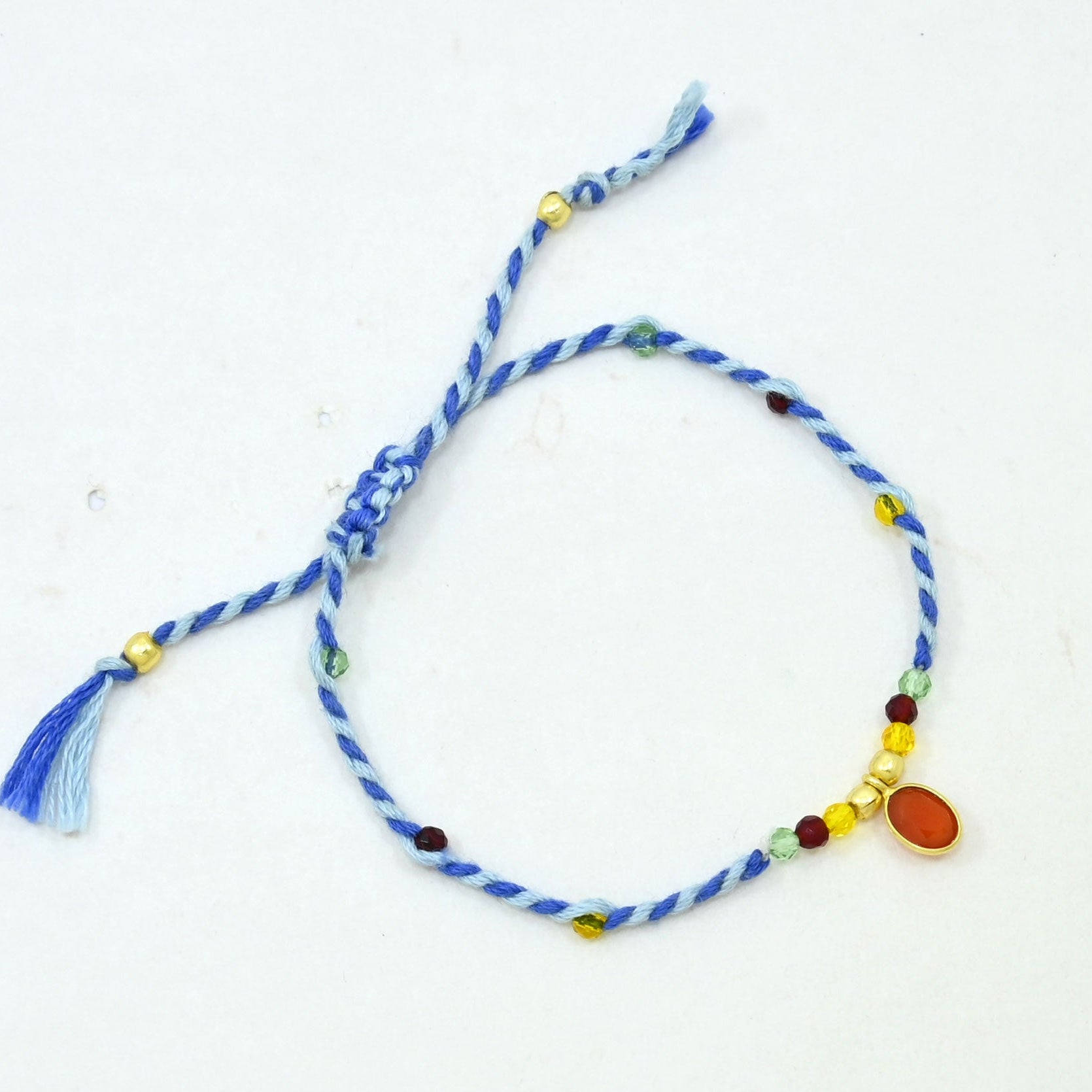 A blue and white twisted cord bracelet with small multicolored beads and a dangling blue tassel.