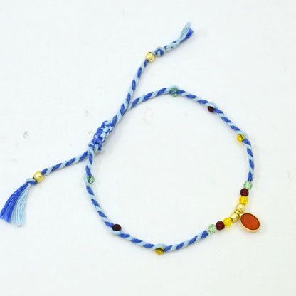 A blue and white twisted cord bracelet with small multicolored beads and a dangling blue tassel.