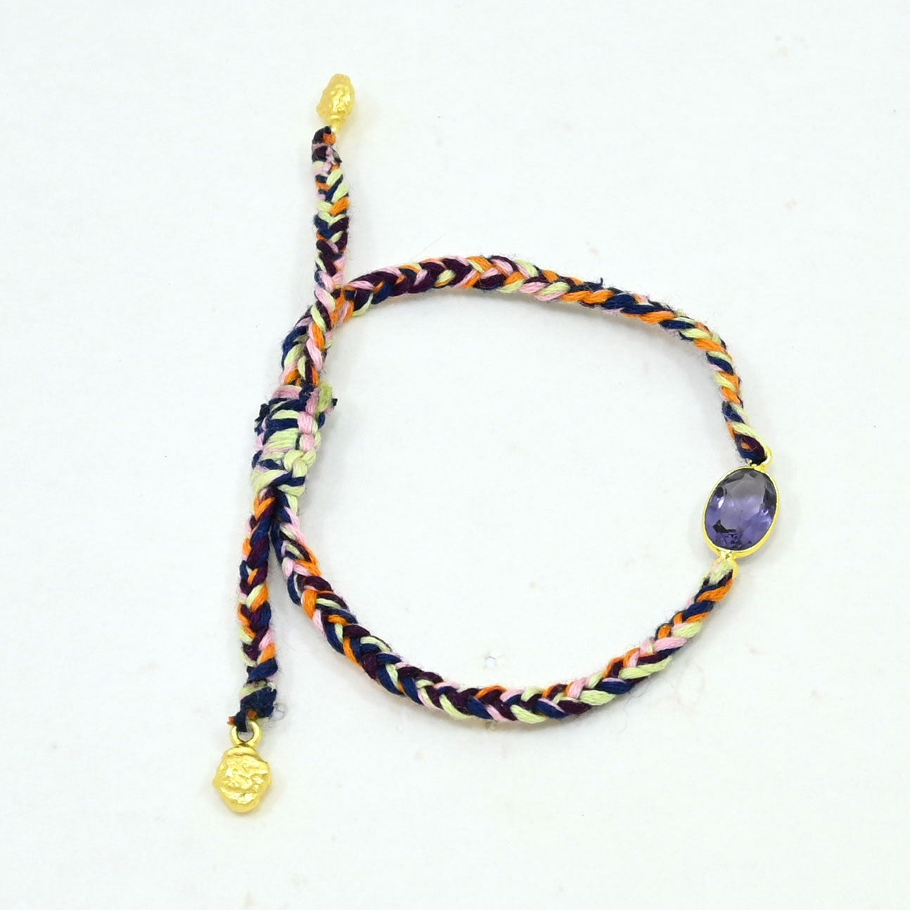 A multicolor braided cord bracelet with gold-toned metal accents, featuring a purple oval stone and a small gold charm.